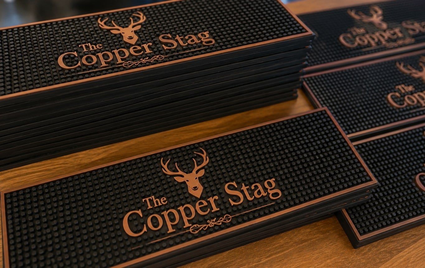 Custom bar mats with logo laid out along a bar rail